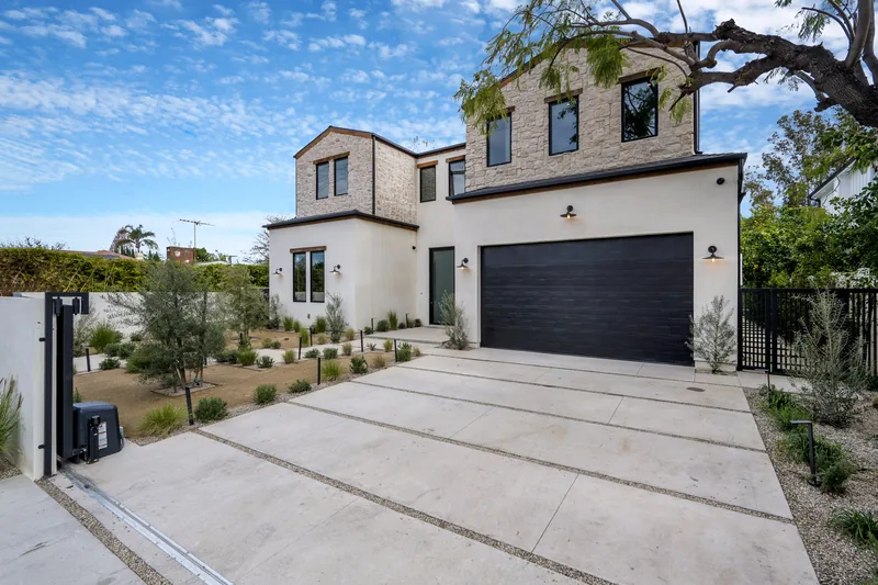 Stucco home with a broad concrete drive below a dry hillside