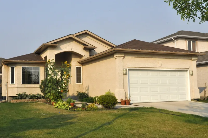 Tan stucco house with an arched entry and an attached two-car garage