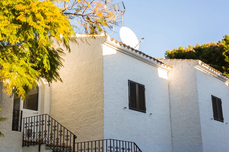 White stucco elevation in full sun with a wrought-iron stair rail