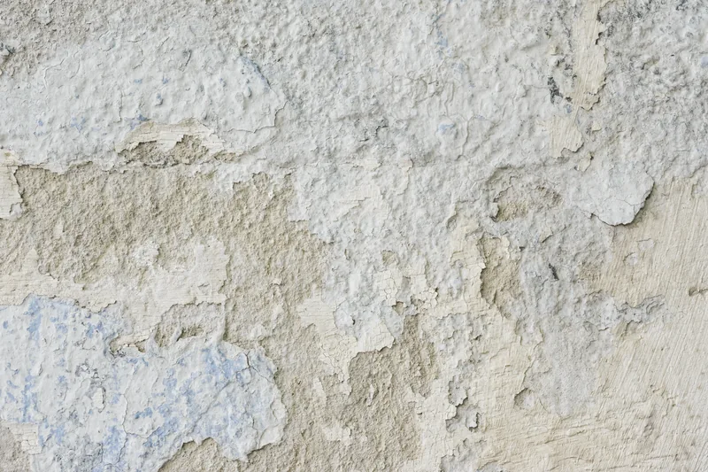 Old coating peeling and flaking off a stucco wall, the surface a repaint has to be prepared from